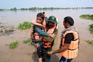 Rescue personnel helps to evacuate a family from the flooded area at Mandi Faizabad district Nankana