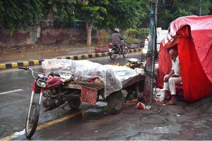 A girl rides her scooty through the rain-soaked streets of the city during a monsoon downpour