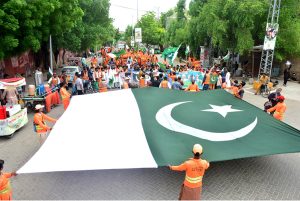 Workers of Sindh Solid Waste Management Board holding rally with displaying huge national flag during the 78th Independence Day and Maarka-E-Haq celebrations at Radio Pakistan Road