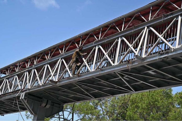 A worker is busy painting a pedestrian bridge at Zero Point in the Federal Capital