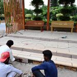 Laborers busy installing new tiles on the steps of a sitting area of a bus stop as part of ongoing renovation work in front of Allama Iqbal Park at Murree Road.
