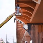A worker busy painting the underside of a flyover while standing in a crane-mounted basket as part of ongoing maintenance work at Peshawar mor interchange in the Federal Capital.