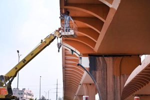 A worker busy painting the underside of a flyover while standing in a crane-mounted basket as part of ongoing maintenance work at Peshawar mor interchange in the Federal Capital.