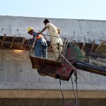 Workers busy welding during the construction work of 10th Avenue Flyover with the help of a crane in the Federal Capital
