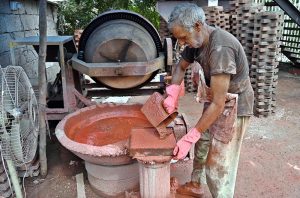A laborer is busy preparing tuff tiles at his workplace near Pindora area.