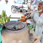 A vendor roasting corn cob on his roadside setup at Chungi No 09