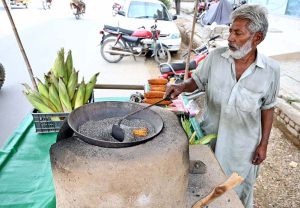 A vendor roasting corn cob on his roadside setup at Chungi No 09