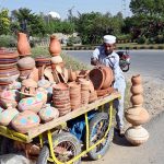 A vendor arranging and displaying clay-made items to attract customers near G-9 area in the Federal Capital