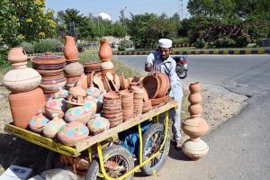 A vendor arranging and displaying clay-made items to attract customers near G-9 area in the Federal Capital