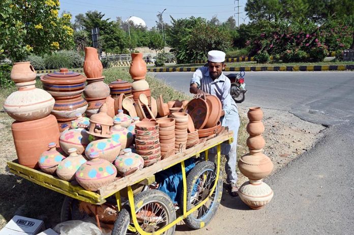 A vendor arranging and displaying clay-made items to attract customers near G-9 area in the Federal Capital