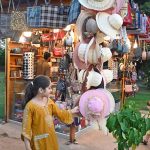 A young girl shows a keen interest in caps displays on a stall at Lake View Park