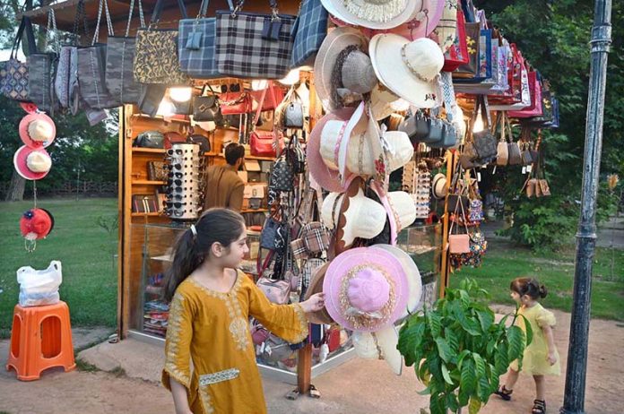 A young girl shows a keen interest in caps displays on a stall at Lake View Park