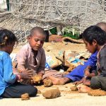 A tension-free age of childhood, as nomadic children enjoy play with mud on the roadside in Latifabad