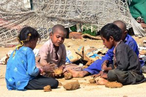 A tension-free age of childhood, as nomadic children enjoy play with mud on the roadside in Latifabad