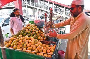 A vendor busy extracting sweet lime juice for customers at his roadside stall.