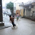 Children are enjoying in the street during rain that experienced the city