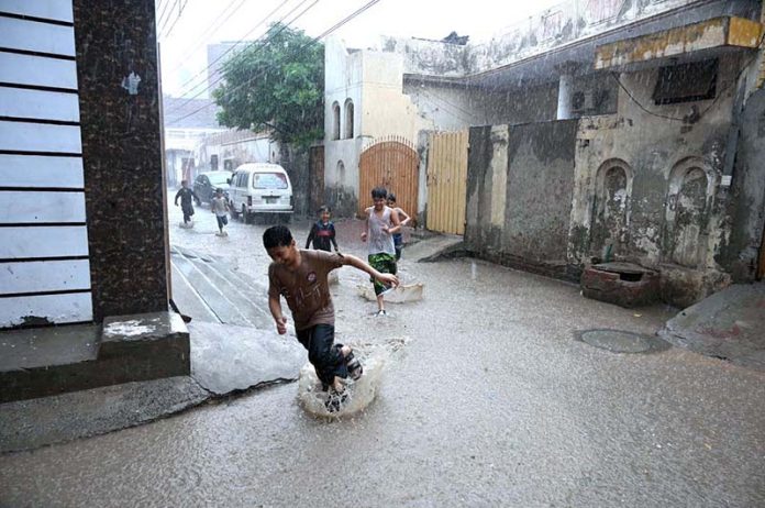 Children are enjoying in the street during rain that experienced the city