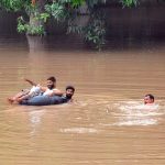 Flood-affected villagers wade through the flood waters toward the safe place