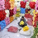 A vendor prepares a bouquet with colorful artificial flowers in his shop at Bani Market