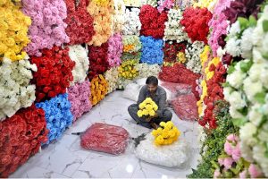 A vendor prepares a bouquet with colorful artificial flowers in his shop at Bani Market