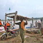 Flood-affected villagers transport their household items to safer locations as floodwater inundates their homes