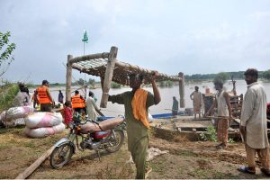 Flood-affected villagers transport their household items to safer locations as floodwater inundates their homes