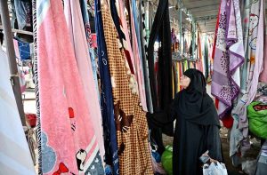 Women selects and purchases used cloth pieces from the I-9/4 weekly bazaar in the Federal Capital.