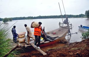 Flood-affected villagers transport their household items to safer locations as floodwater inundates their homes