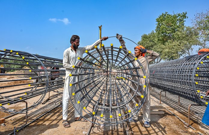 Labourers are busy preparing iron structures for the pillars during the construction of the T-Chowk Flyover, which is part of the ongoing development work