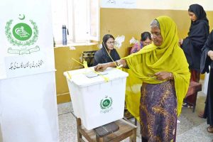 A woman casts her vote at a polling station during the Local Government by-election in UC 112, Latifabad.
