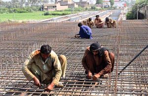 Labourers busy in construction work of new bridge over the Phulile canal during development work in the city.