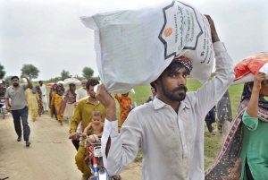 A flood-affected resident carries a bag of flour after receiving food aid distributed by Mr. Rashid Uddin, General Manager of Serena Hotel Faisalabad, and AC Tandlianwala Azka Sahar in Tandlianwala.