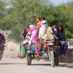 Families traveling on a tricycle rickshaw in a rural area