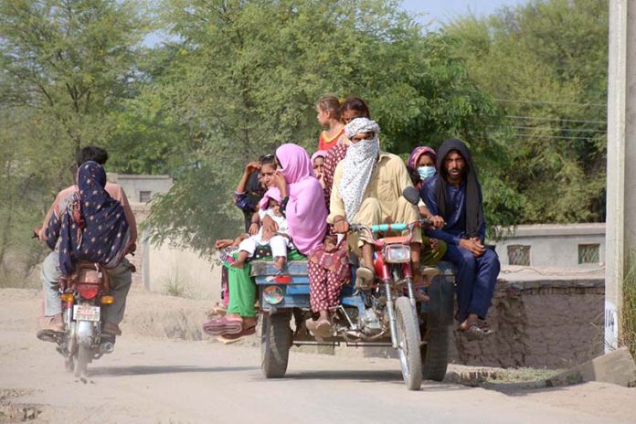 Families traveling on a tricycle rickshaw in a rural area