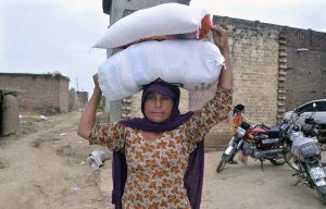A flood-affected resident carries a bag of flour after receiving food aid distributed by Mr. Rashid Uddin, General Manager of Serena Hotel Faisalabad, and AC Tandlianwala Azka Sahar in Tandlianwala.