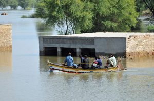 A youngster standing on a rooftop with salvaged household items after floodwater inundated houses following river overflow. Heavy flooding has disrupted life across several districts in South Punjab.