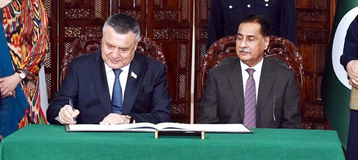 Speaker of the Legislative Chamber of the Oliy Majlis of Uzbekistan, Nuriddin Ismoilov, inscribing his remarks in the visitors’ book at Parliament House