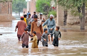 Flood-affected villagers wade through the flood waters toward the safe place