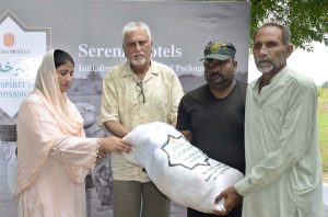 A flood-affected resident carries a bag of flour after receiving food aid distributed by Mr. Rashid Uddin, General Manager of Serena Hotel Faisalabad, and AC Tandlianwala Azka Sahar in Tandlianwala.