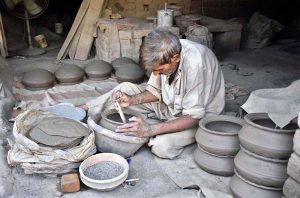 A porter skillfully molding traditional clay pots at his work place at Chungi Amar Sadhu.