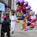 A street vendor displaying various colorful balloons to attract customers at the roadside.