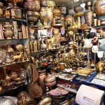 A vendor arranging antique brass items at his shop in a local market