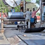 Workers are busy folding large metal sheets on a rolling machine