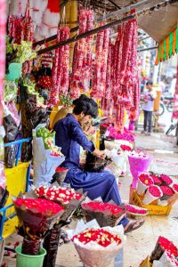 A vendor busy preparing flower bouquets to attract customers at flower market, Banni Chowk.