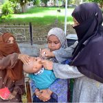 A lady health worker busy in administering polio drops to child during anti polio vaccination campaign in pritabad Hospital at Norani basti