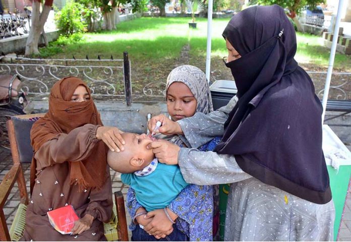 A lady health worker busy in administering polio drops to child during anti polio vaccination campaign in pritabad Hospital at Norani basti