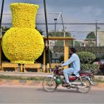 A huge pot, decorated with artificial flowers for city beautification, is displayed along Murree Road