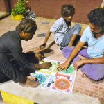 People enjoying a game of ludo while sitting on the footpath outside Radio Pakistan Road