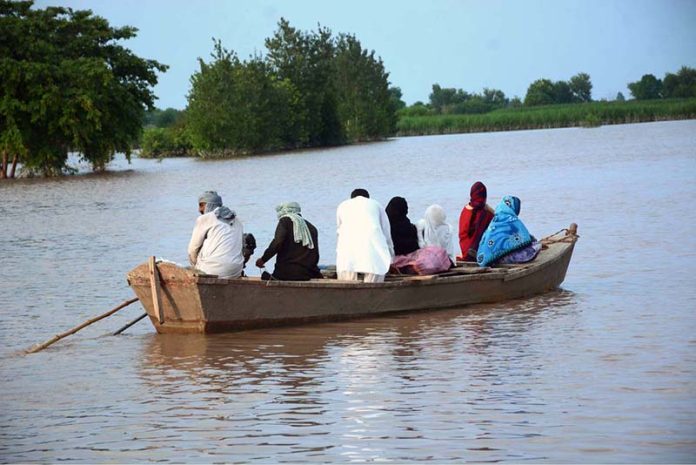 A flood-affected family being rescued by boat to cross floodwaters and move to a safer place in Bhuwana Tehsil near the Chenab River