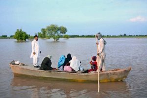 A flood-affected family being rescued by boat to cross floodwaters and move to a safer place in Bhuwana Tehsil near the Chenab River